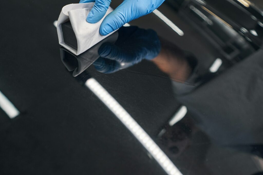 Car detailing worker applying ceramic coating on car varnish